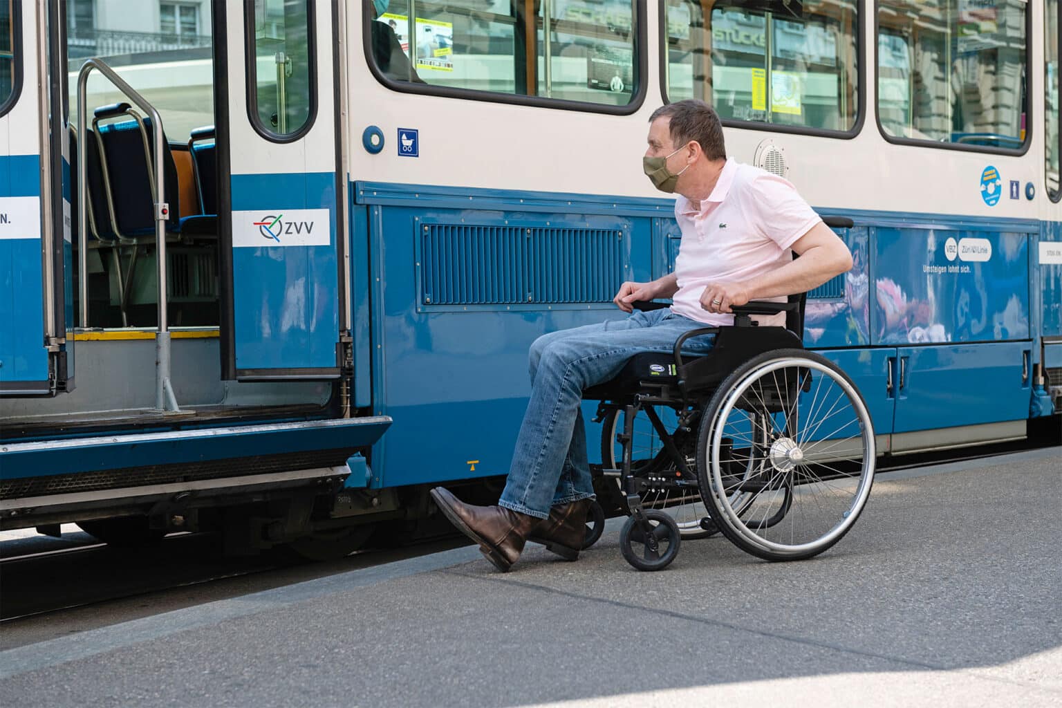 Ein Mann im Rollstuhl vor einem Zürcher Tram.